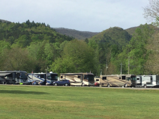 Motorhomes parked with beautiful green hills in the background.